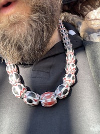 a man with a beard wearing a necklace with red and white beads