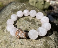 a bracelet with a pink stone and a wooden bead