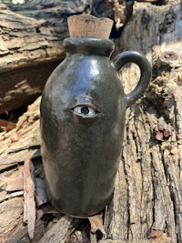 a black jug sitting on a piece of wood