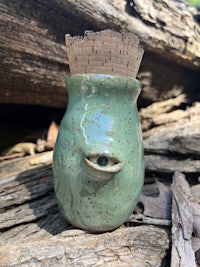 a green mug sitting on a piece of wood