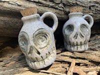 two skull jugs sitting on top of some wood