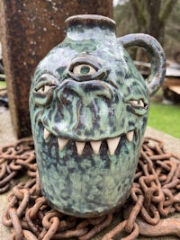 a green jug sitting on a chain on the ground