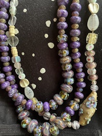 a purple and gold beaded necklace on a black bag