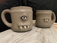 two monster mugs with eyes on them